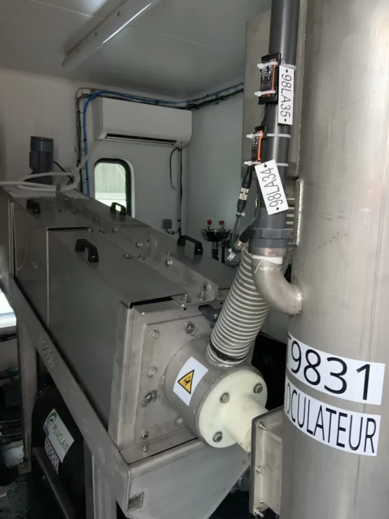 presse à vis ADEQUAPRESS pour la déshydratation de boues industrielles dans un atelier en container